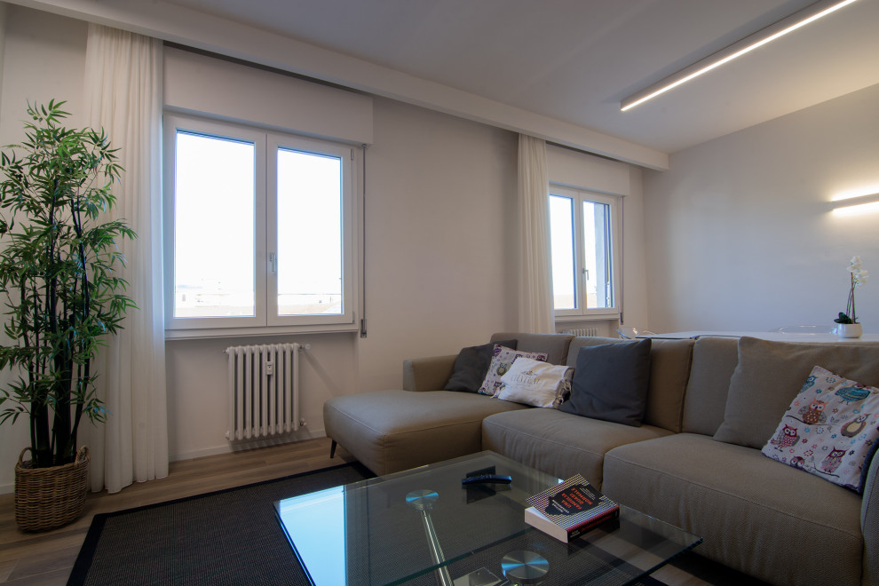 Immagine di un ampio soggiorno minimal aperto con libreria, pareti bianche, pavimento in gres porcellanato, parete attrezzata e pavimento beige