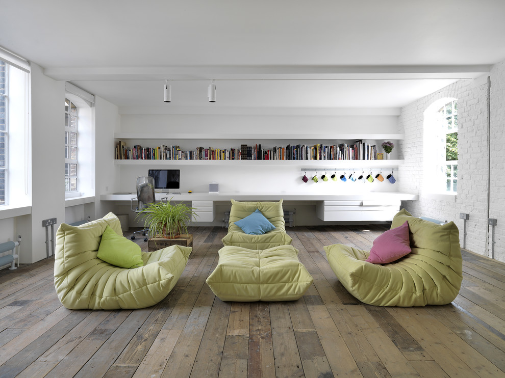 Ejemplo de sala de estar abierta urbana sin televisor con paredes blancas, suelo de madera clara y suelo gris