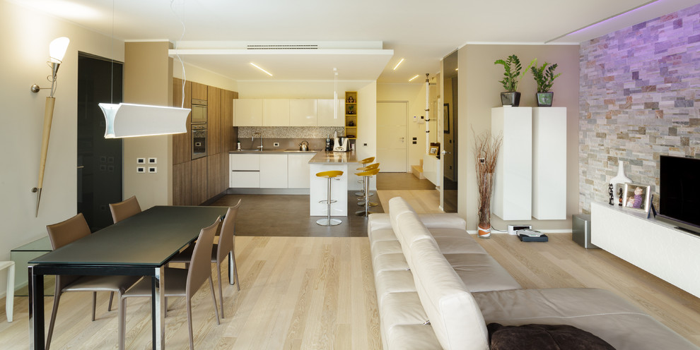 Foto de salón abierto actual extra grande con paredes beige, suelo de madera clara y televisor independiente