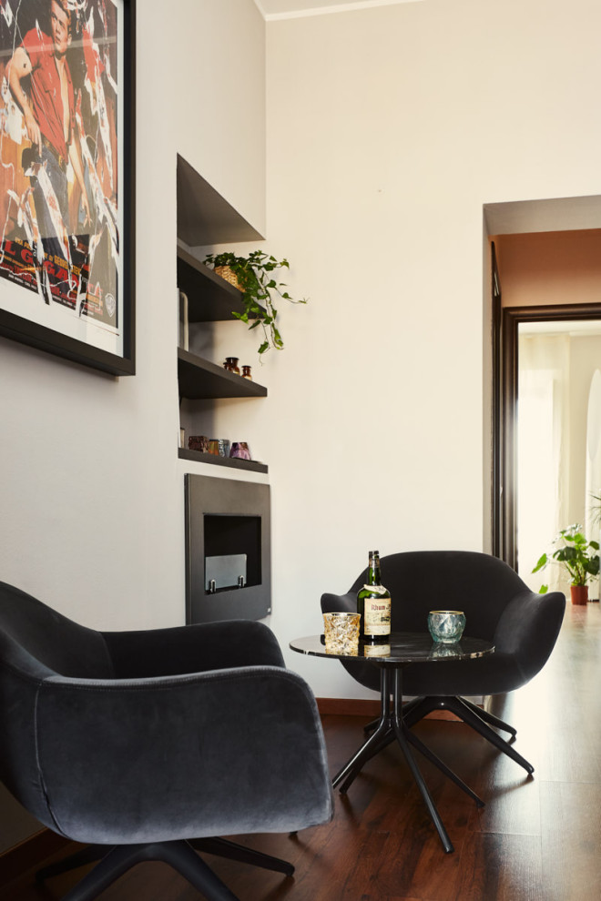 Modernes Wohnzimmer mit Hausbar, weißer Wandfarbe, braunem Holzboden, Hängekamin, Kaminumrandung aus Metall und braunem Boden in Mailand