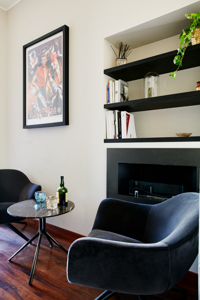 Foto di un soggiorno minimalista con angolo bar, pareti bianche, pavimento in legno massello medio, camino sospeso, cornice del camino in metallo e pavimento marrone