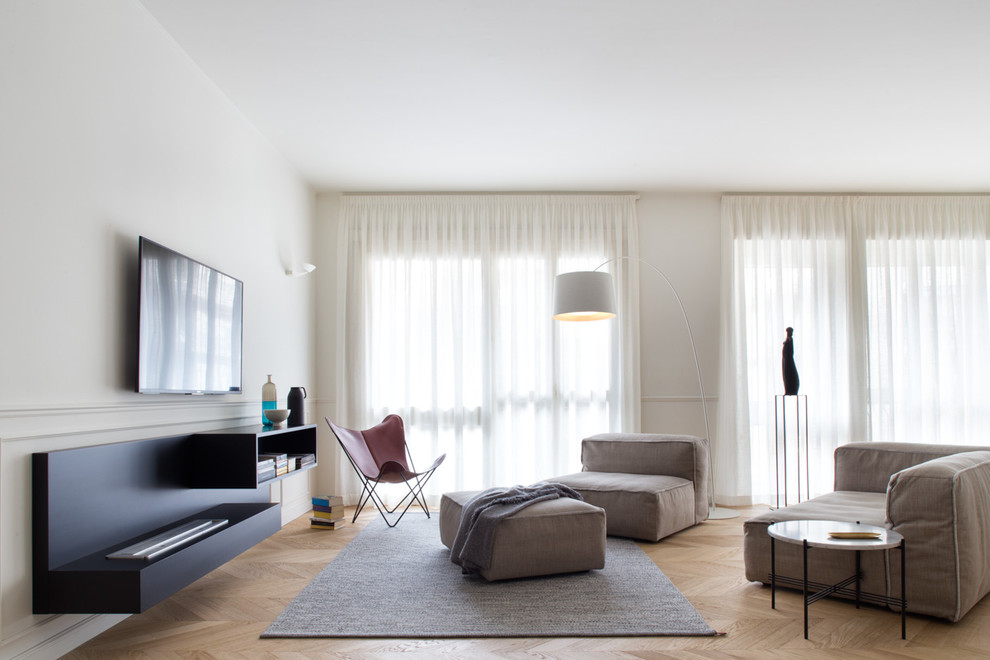 Foto de sala de estar abierta contemporánea sin chimenea con paredes blancas, suelo de madera clara y televisor colgado en la pared