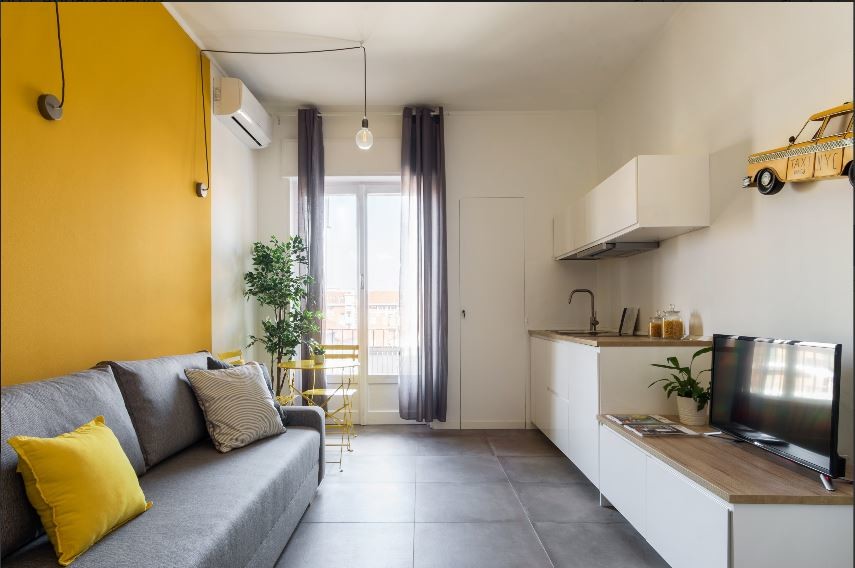 Bild på ett litet funkis allrum med öppen planlösning, med gula väggar, klinkergolv i porslin, en inbyggd mediavägg och grått golv