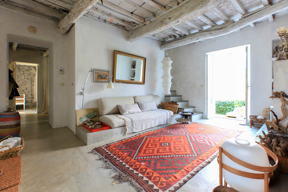 Réalisation d'un salon méditerranéen ouvert avec un mur blanc, sol en béton ciré et un sol gris.