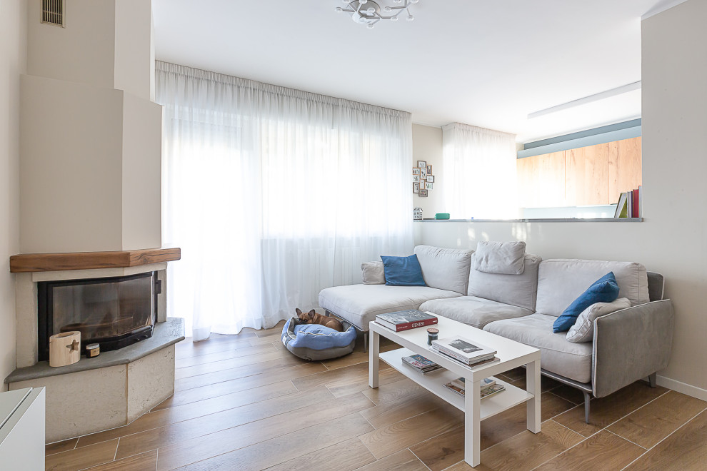 Idee per un soggiorno scandinavo di medie dimensioni e aperto con pareti beige, pavimento in gres porcellanato, camino ad angolo e parete attrezzata