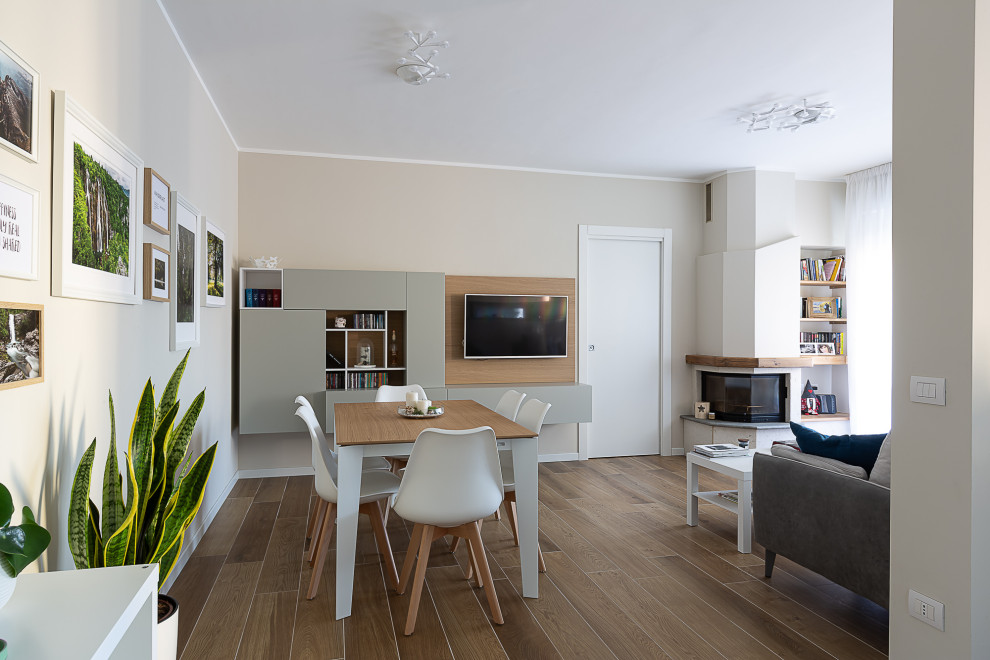 На фото: открытая гостиная комната среднего размера в современном стиле с бежевыми стенами, полом из керамогранита, угловым камином, телевизором на стене и коричневым полом