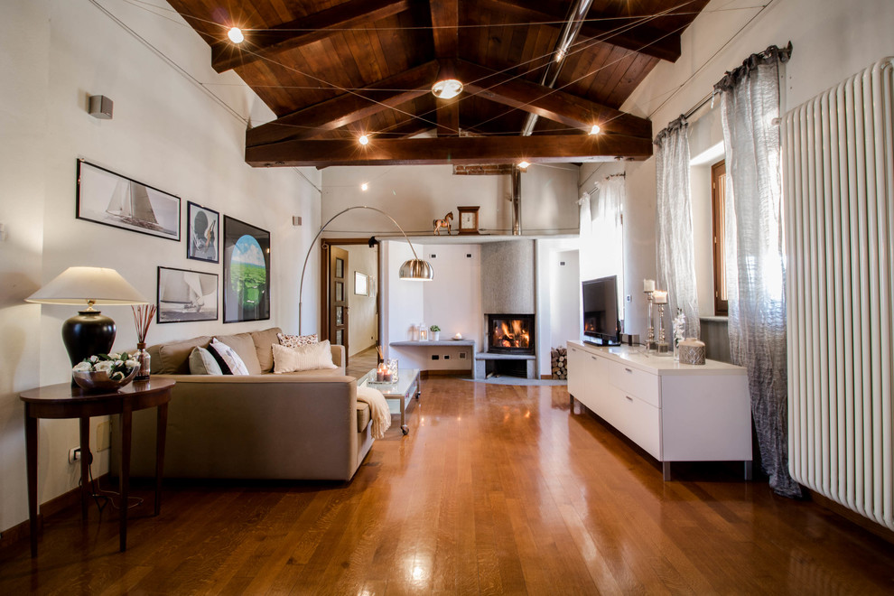 Idée de décoration pour un grand salon champêtre ouvert avec un téléviseur indépendant, un mur blanc, un poêle à bois, un manteau de cheminée en métal, un sol en bois brun et un sol orange.