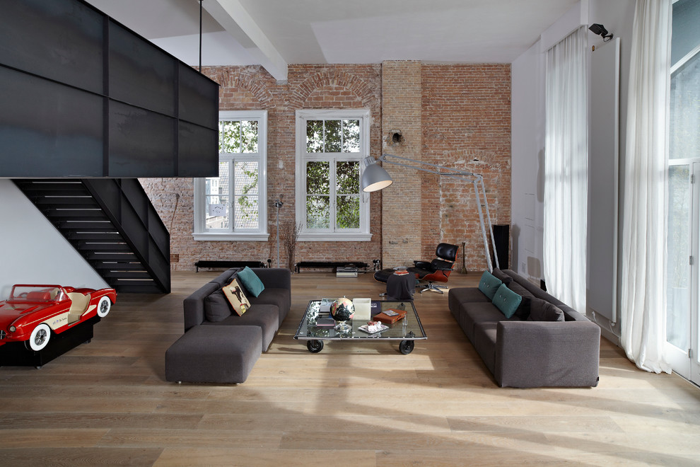 Diseño de salón urbano sin chimenea y televisor con paredes blancas y suelo de madera clara