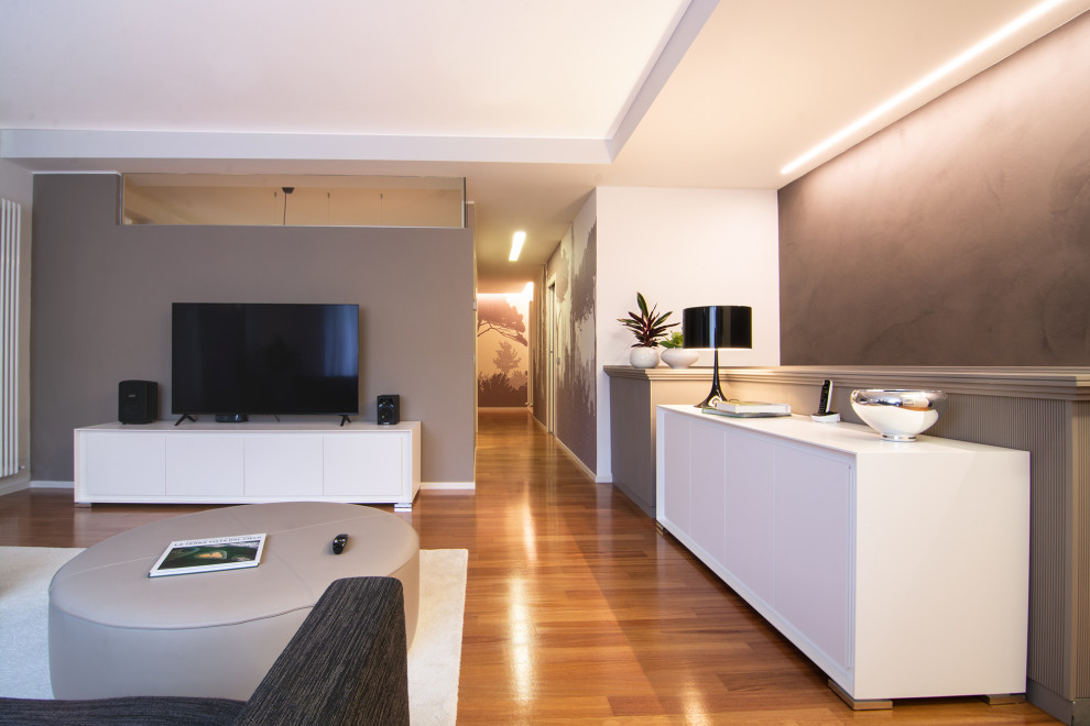 На фото: большая изолированная гостиная комната в современном стиле с коричневыми стенами, деревянным полом, телевизором на стене, коричневым полом и обоями на стенах с