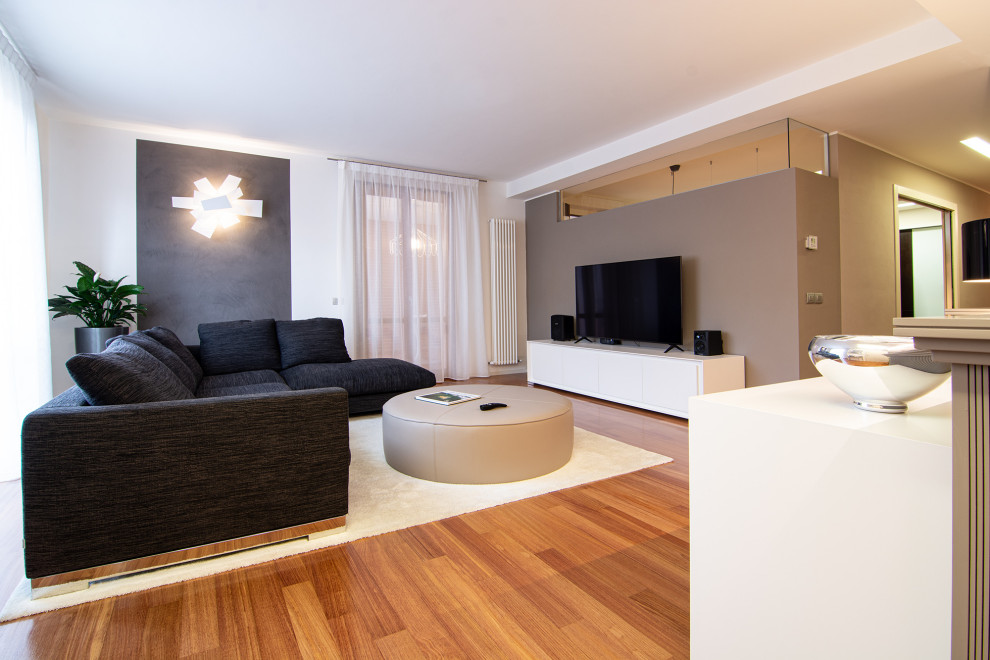 Immagine di un soggiorno design di medie dimensioni e aperto con sala formale, pareti marroni, pavimento in legno verniciato, TV a parete e carta da parati