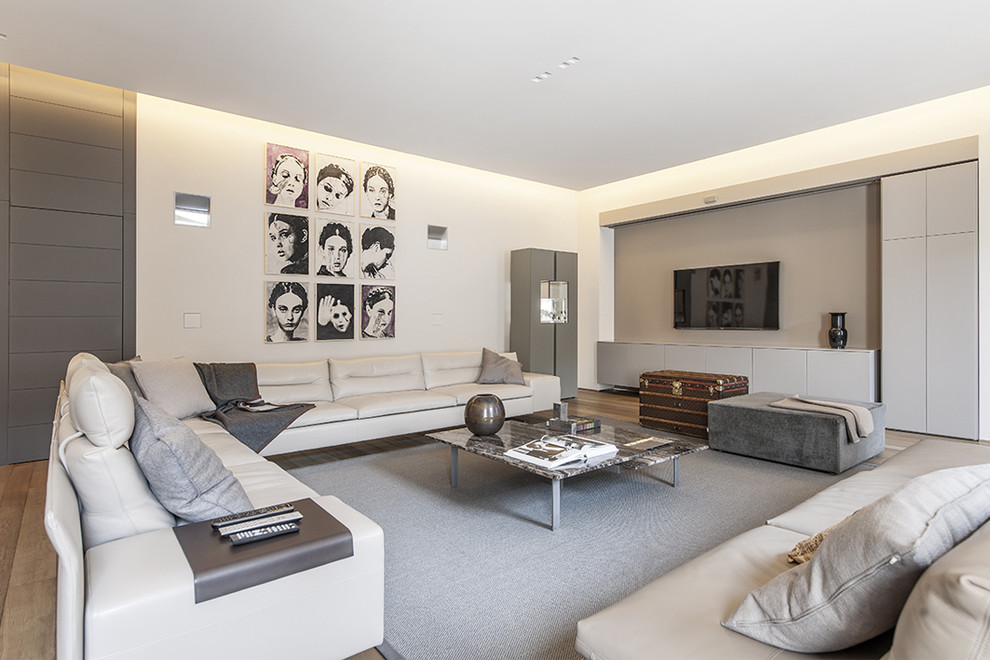 На фото: большая изолированная гостиная комната в современном стиле с белыми стенами и телевизором на стене