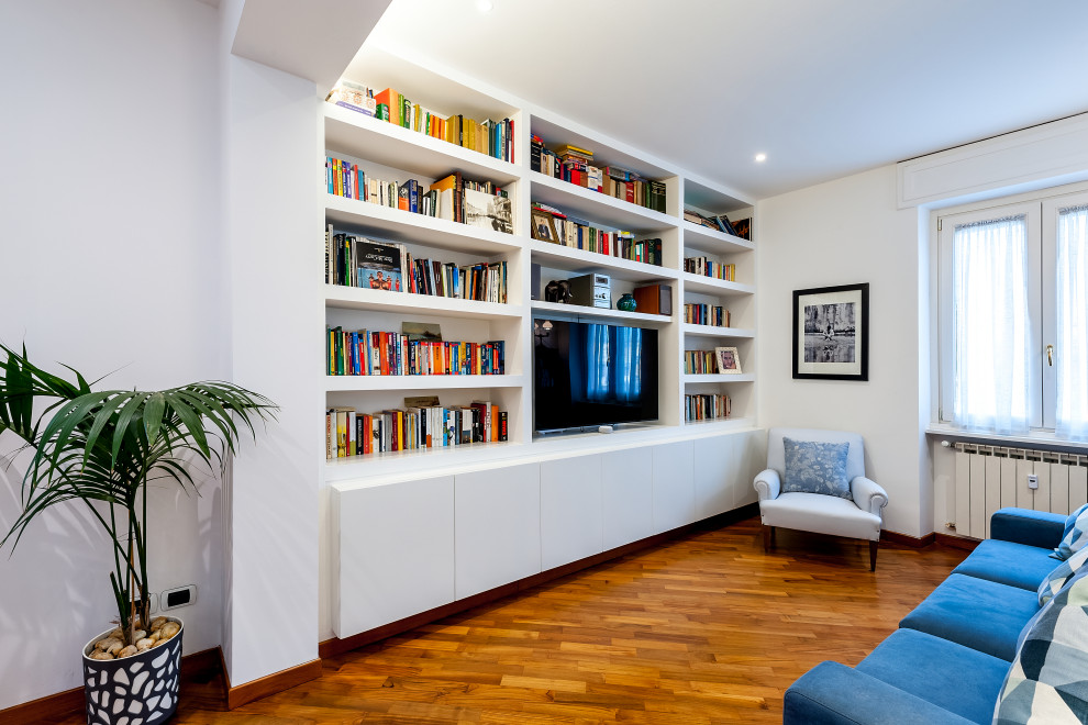 Foto de salón actual con paredes blancas, suelo de madera en tonos medios, pared multimedia y suelo marrón