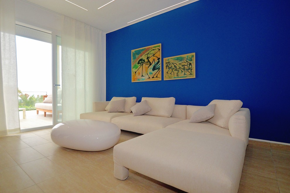 Inredning av ett modernt stort allrum med öppen planlösning, med blå väggar, klinkergolv i porslin, en väggmonterad TV och beiget golv