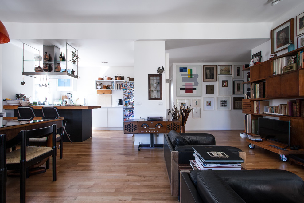 Immagine di un soggiorno bohémian di medie dimensioni e aperto con libreria, pareti bianche, pavimento in legno massello medio, parete attrezzata e pavimento marrone
