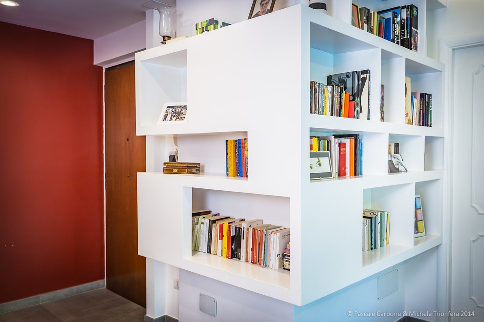Источник вдохновения для домашнего уюта: открытая гостиная комната в стиле модернизм с с книжными шкафами и полками, красными стенами, полом из керамогранита и серым полом
