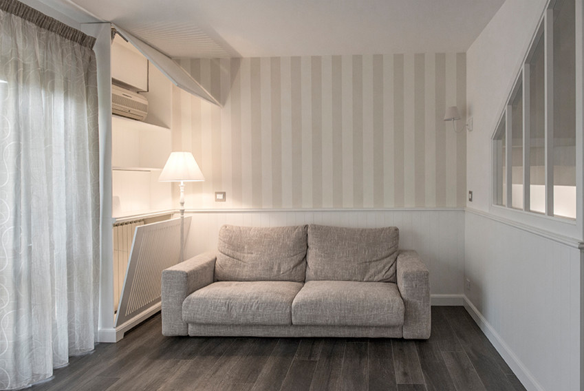 Imagen de sala de estar abierta romántica de tamaño medio con paredes blancas, suelo de baldosas de porcelana, televisor colgado en la pared y suelo marrón