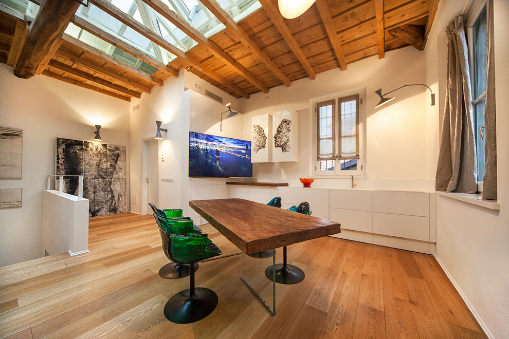 Imagen de salón abierto actual grande con paredes blancas, suelo de madera en tonos medios y televisor colgado en la pared