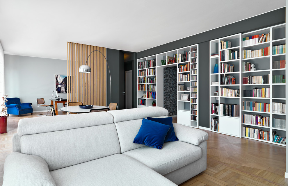Idée de décoration pour un salon minimaliste ouvert avec une bibliothèque ou un coin lecture, un mur gris et parquet clair.