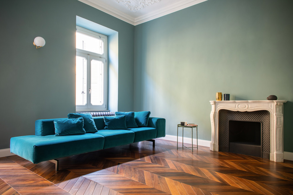 Modernes Wohnzimmer mit grüner Wandfarbe, Kamin, Kaminumrandung aus Stein und dunklem Holzboden in Turin