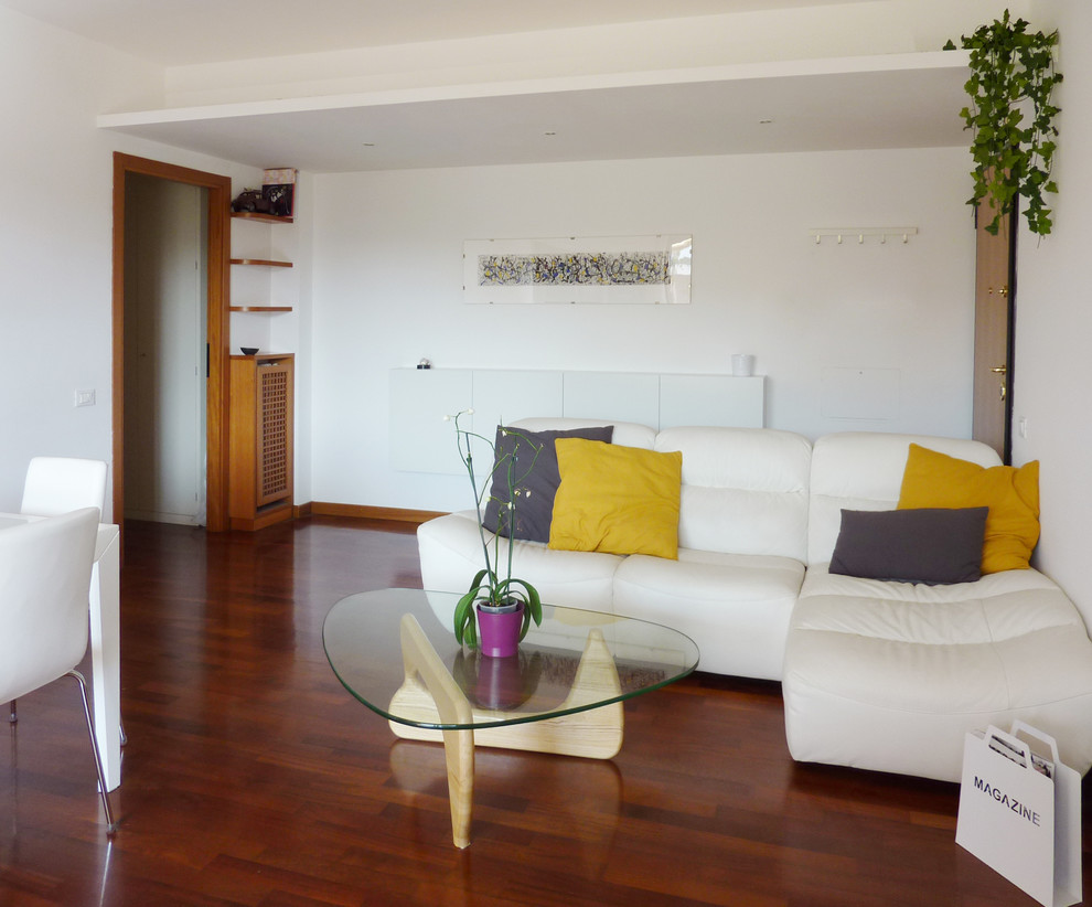 Diseño de salón abierto actual de tamaño medio con paredes blancas, suelo de madera en tonos medios y televisor independiente