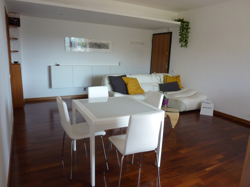 Mittelgroßes, Offenes Modernes Wohnzimmer mit weißer Wandfarbe, braunem Holzboden und freistehendem TV in Rom