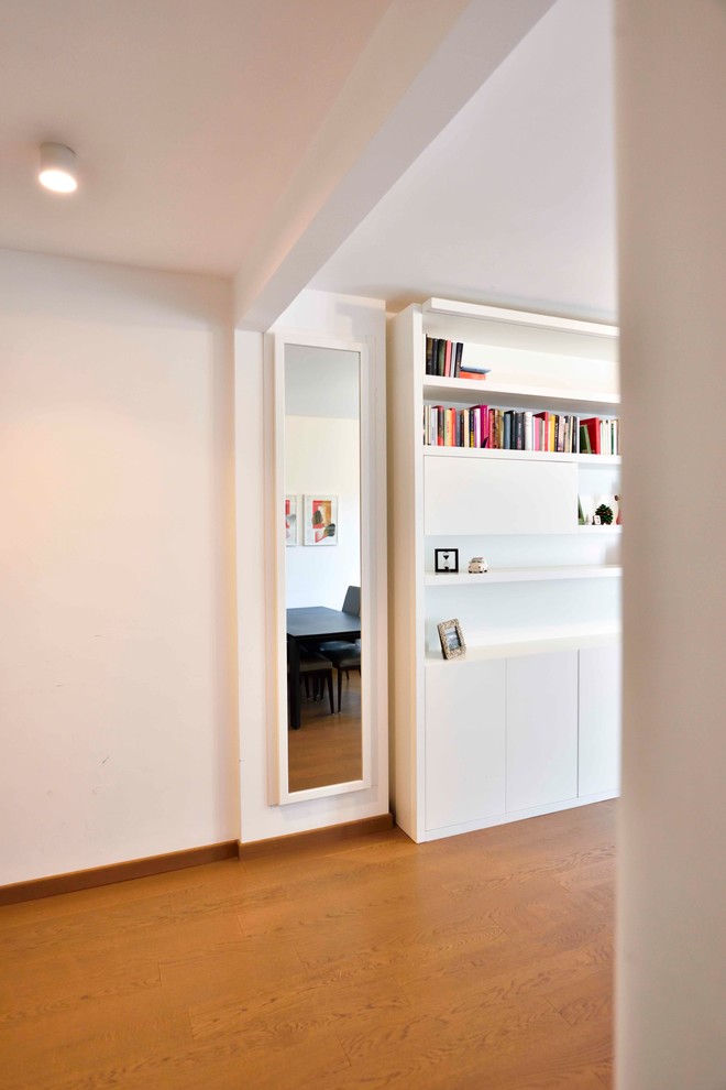 Идея дизайна: открытая гостиная комната среднего размера в современном стиле с белыми стенами, с книжными шкафами и полками, деревянным полом и коричневым полом