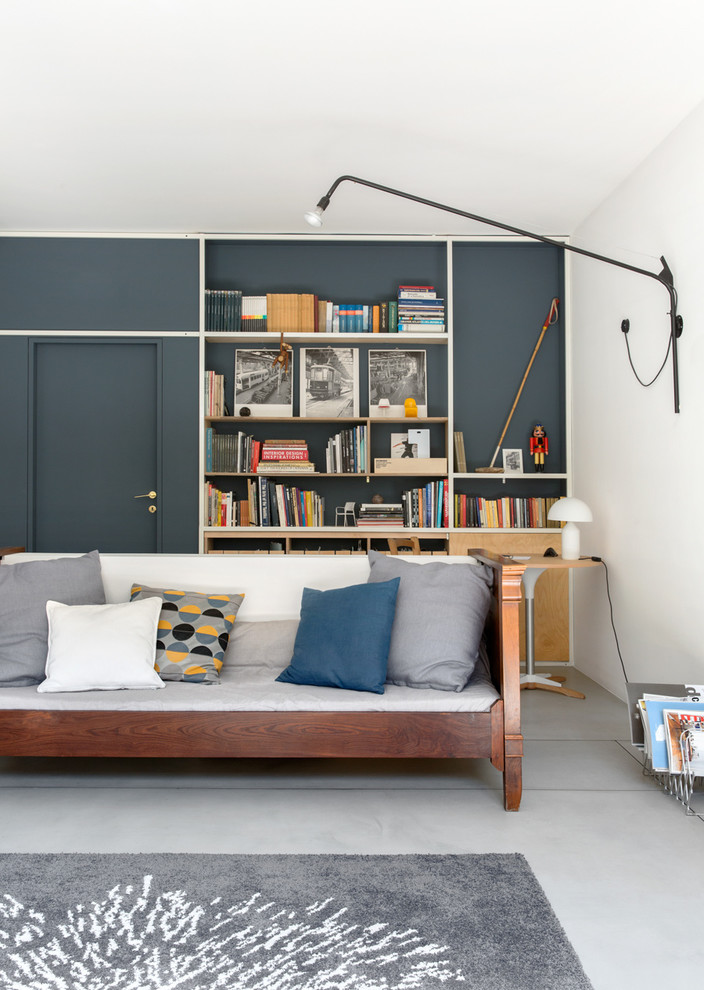 На фото: огромная двухуровневая гостиная комната в стиле лофт с с книжными шкафами и полками, синими стенами, бетонным полом и серым полом без телевизора с