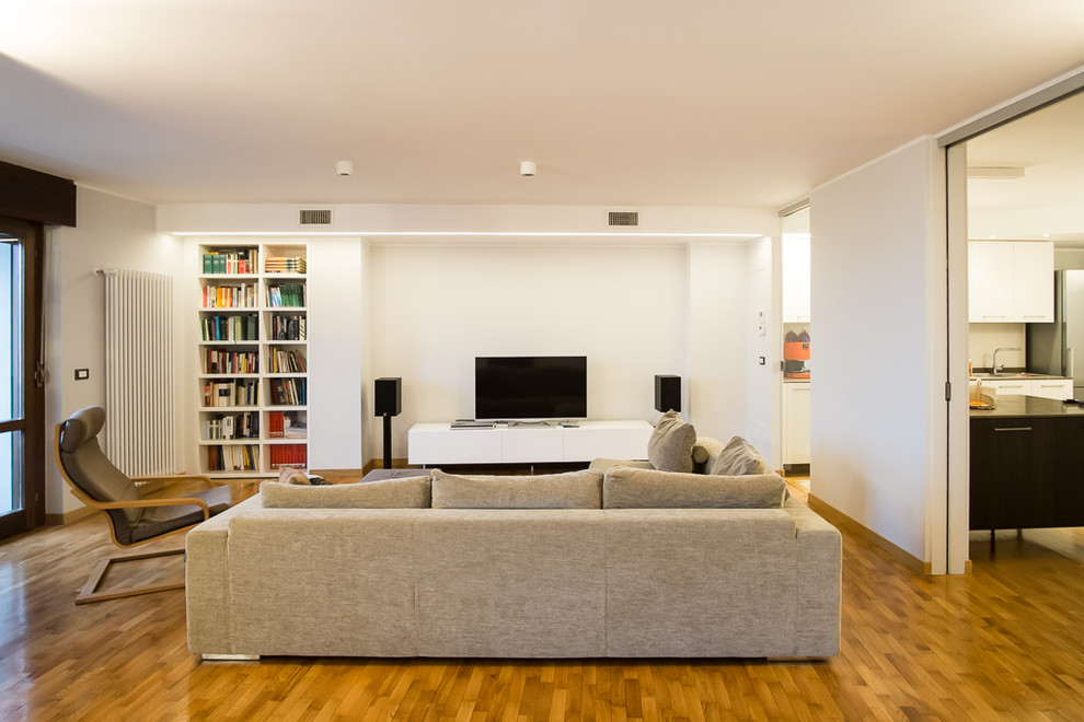 Esempio di un ampio soggiorno design aperto con libreria, pareti bianche e parquet chiaro