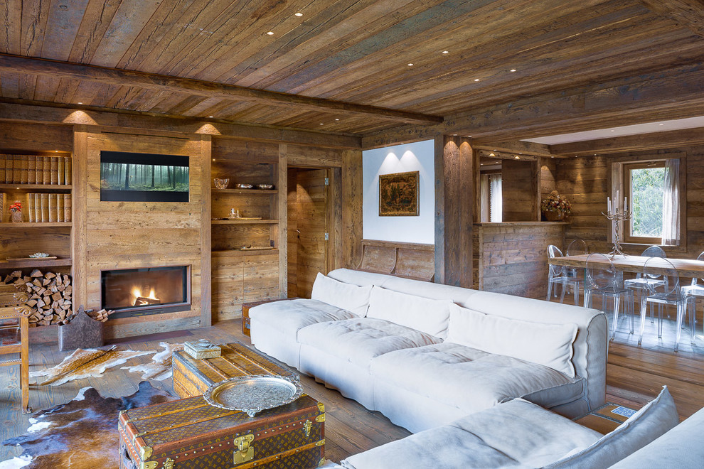 Идея дизайна: гостиная комната в стиле рустика с темным паркетным полом, стандартным камином и фасадом камина из дерева