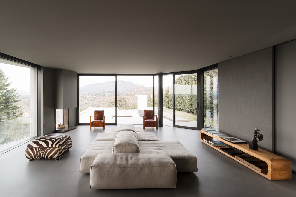 This is an example of a modern living room in Milan with grey walls, concrete flooring, a corner fireplace and grey floors.