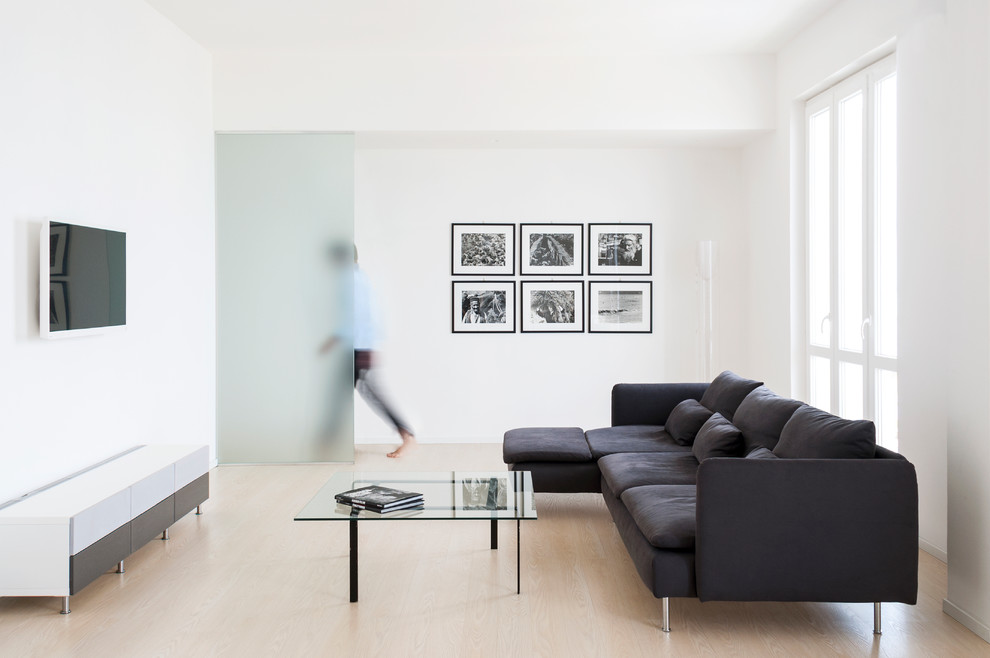 Cette photo montre une salle de séjour moderne ouverte avec un mur blanc, sol en stratifié et un téléviseur fixé au mur.