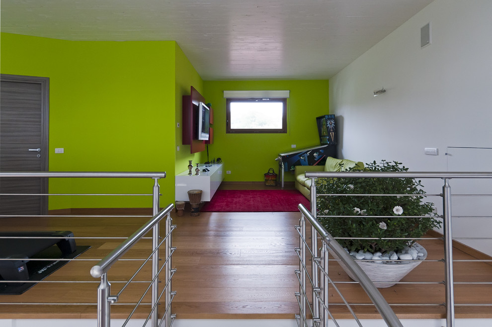 Ispirazione per un soggiorno country di medie dimensioni e stile loft con sala giochi, pareti verdi, pavimento in legno massello medio e TV a parete