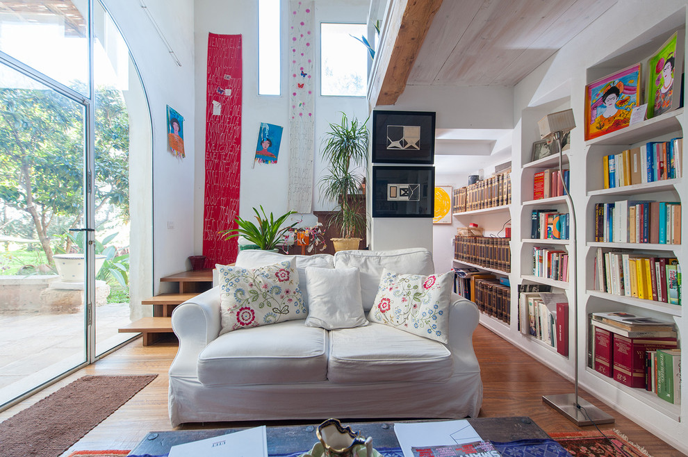 Diseño de biblioteca en casa abierta ecléctica de tamaño medio con paredes blancas, suelo de madera en tonos medios y suelo marrón