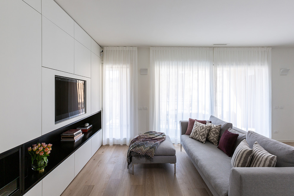 Idee per un soggiorno moderno di medie dimensioni con pareti bianche, parquet chiaro e parete attrezzata