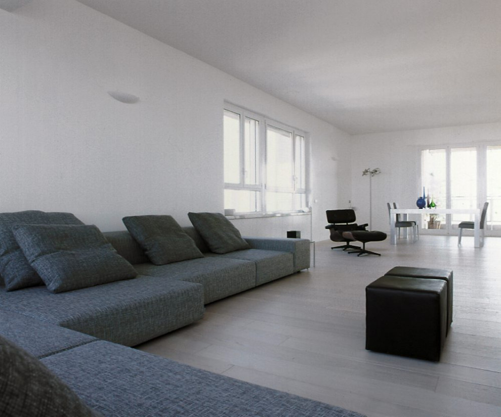 Foto de salón tipo loft minimalista grande con paredes blancas, suelo de madera clara, televisor retractable y suelo blanco
