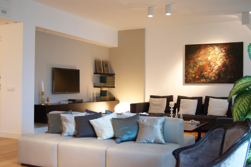 Ejemplo de sala de estar moderna con paredes blancas, suelo de madera clara y televisor colgado en la pared