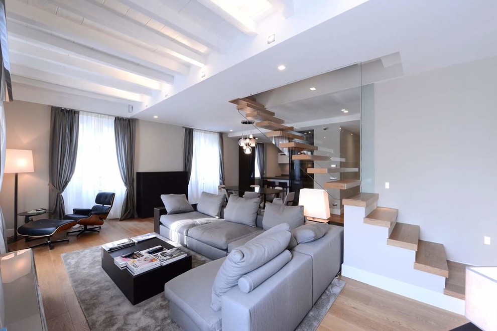 Foto di un grande soggiorno design aperto con pareti grigie e parquet chiaro
