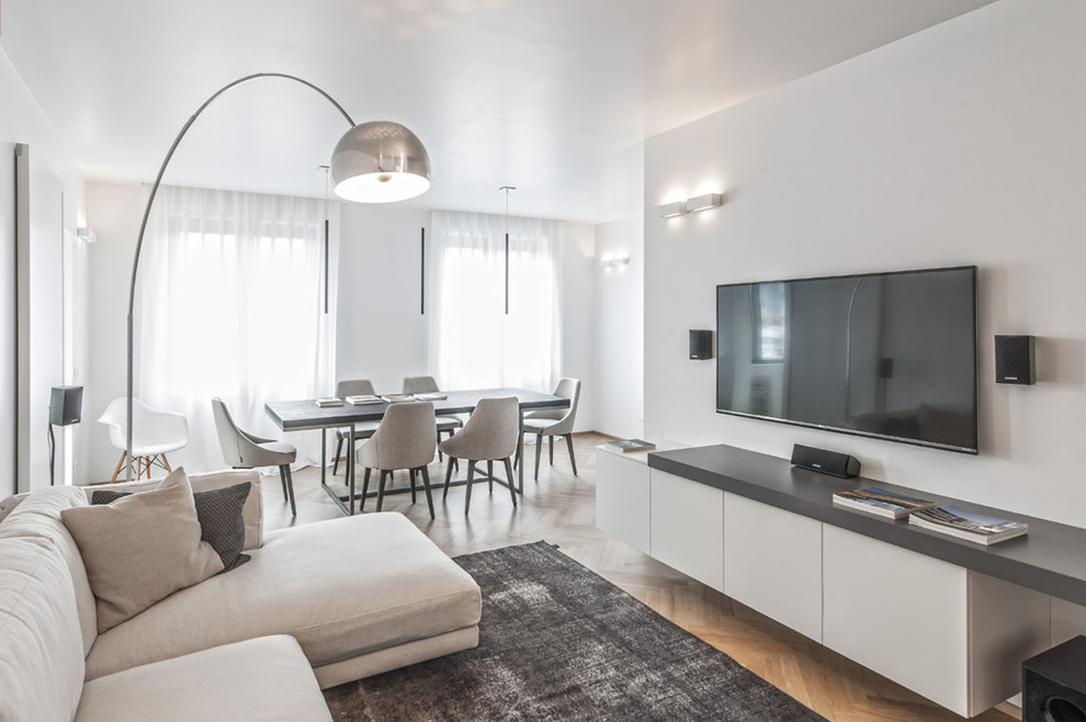 This is an example of a contemporary living room in Milan with white walls, light hardwood flooring and a wall mounted tv.