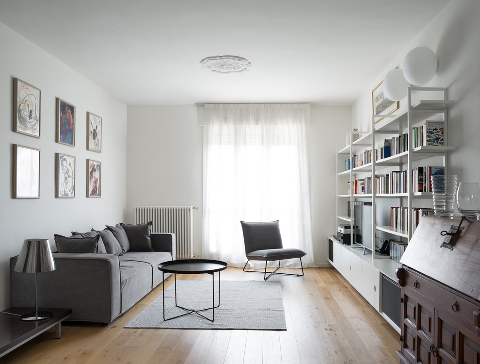 Example of a mid-sized danish open concept medium tone wood floor and brown floor living room library design in Milan with white walls, no fireplace and a media wall