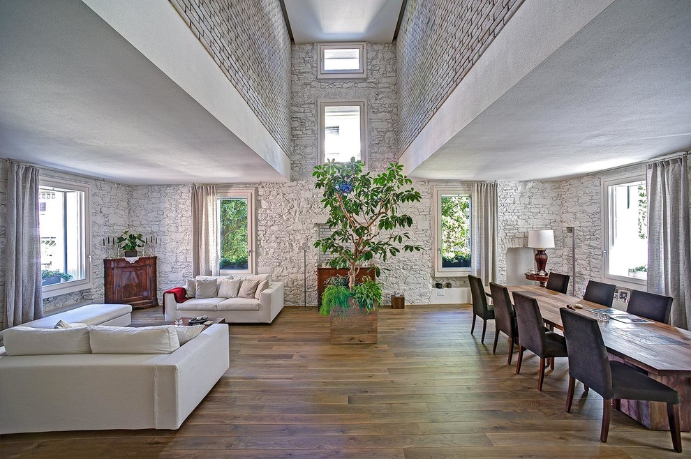 Geräumiges, Fernseherloses, Offenes Modernes Wohnzimmer ohne Kamin mit weißer Wandfarbe und braunem Holzboden in Mailand
