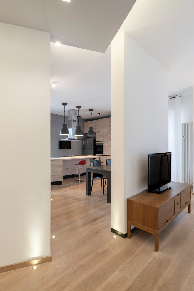 Immagine di un grande soggiorno design aperto con pareti bianche, parquet chiaro, TV autoportante e pavimento beige