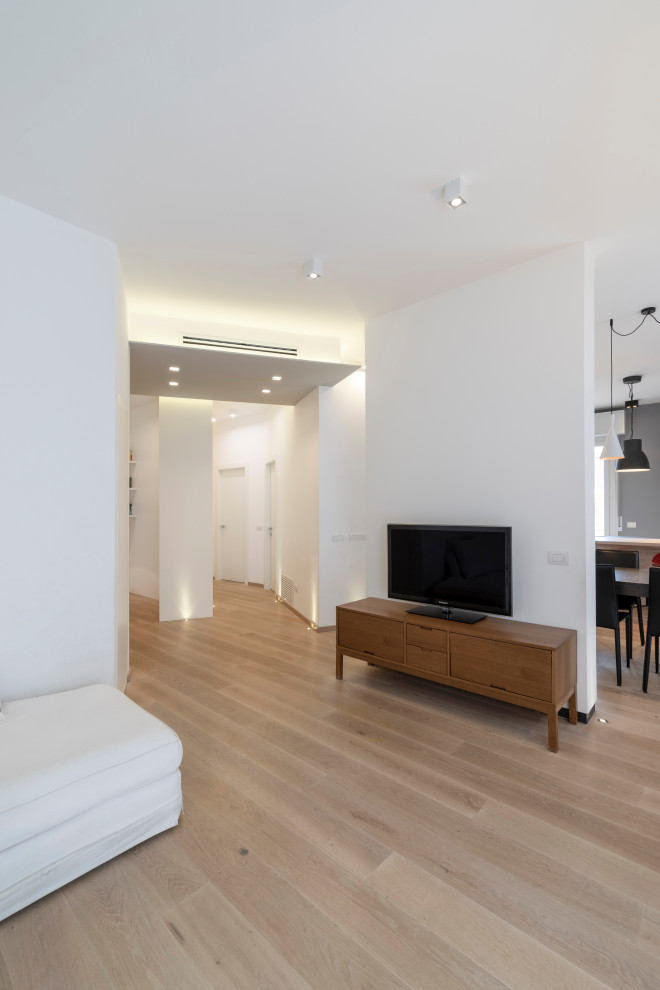 Ispirazione per un soggiorno design aperto con pareti bianche, parquet chiaro, TV autoportante e pavimento beige