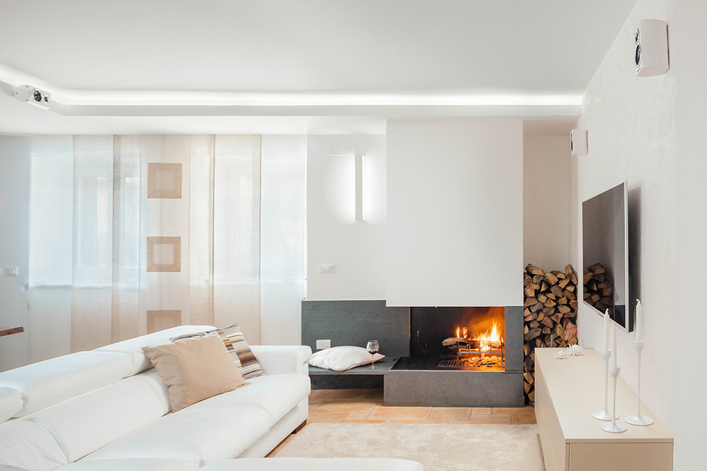 ナポリにあるコンテンポラリースタイルのおしゃれなオープンリビング (白い壁、テラコッタタイルの床、コンクリートの暖炉まわり、コーナー設置型暖炉) の写真