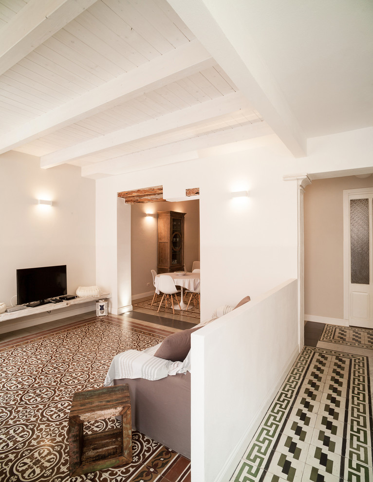 Immagine di un grande soggiorno mediterraneo aperto con pareti bianche, pavimento in terracotta, TV a parete e pavimento marrone