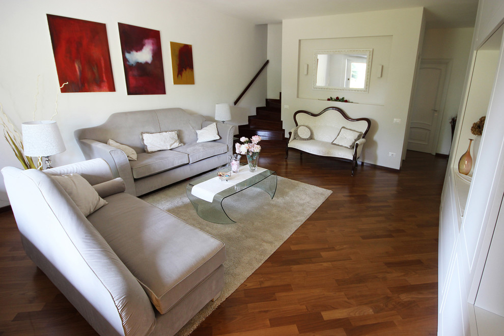 Foto de salón para visitas abierto tradicional de tamaño medio con paredes blancas, suelo de madera oscura, pared multimedia y suelo marrón