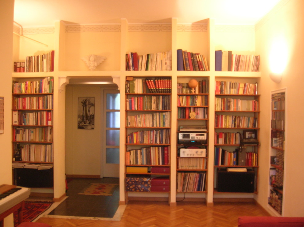 Стильный дизайн: открытая гостиная комната среднего размера в стиле модернизм с с книжными шкафами и полками, желтыми стенами и светлым паркетным полом - последний тренд