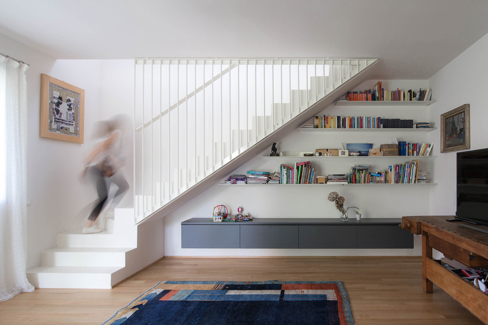Esempio di un soggiorno design con pareti bianche, pavimento in legno massello medio, TV autoportante, pavimento marrone e tappeto
