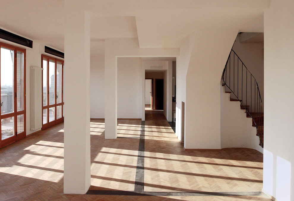 This is an example of a medium sized contemporary mezzanine living room in Bologna with white walls and light hardwood flooring.