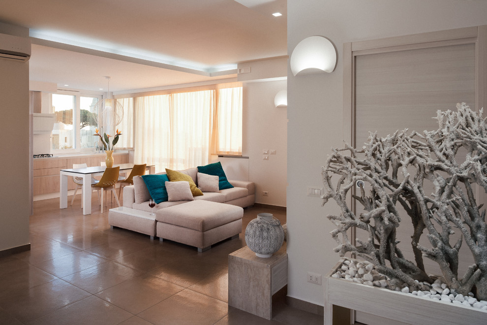 На фото: открытая гостиная комната среднего размера в современном стиле с белыми стенами, полом из керамогранита, стандартным камином, фасадом камина из камня, телевизором на стене и бежевым полом
