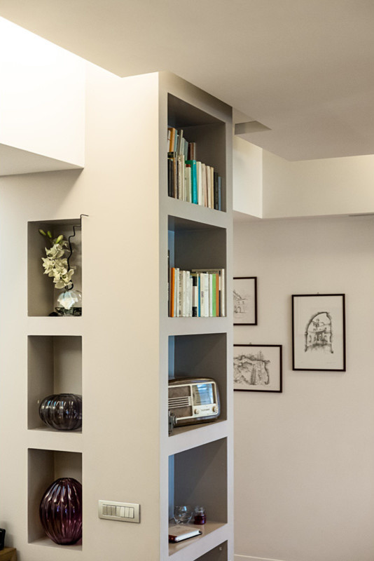 Immagine di un soggiorno contemporaneo aperto e di medie dimensioni con libreria, pareti bianche, parquet chiaro e pavimento beige